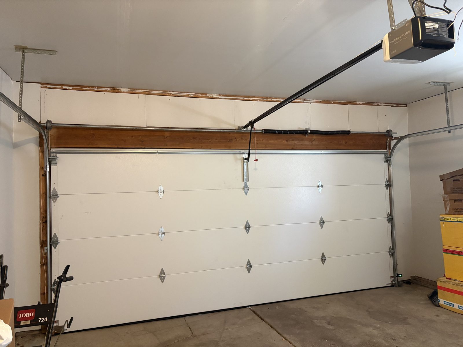 Inside a Colorado Springs garage: Chamberlain opener on the ceiling, rail running to the door, and the red emergency release handle hanging from the trolley.